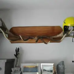 Une idée déco avec bois de cerf : des bois imposants fixés sur une planche de bois, supportant un casque de ski jaune vif.