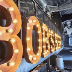 Lettre enseigne lumineuse "BOBSTER" sur fond d'une fresque vintage.
