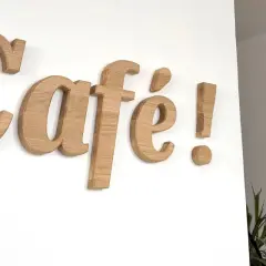 Lettre en bois "Café !" sur un mur blanc. Ces lettres en bois, comme une lettre PVC, apportent une touche chaleureuse.