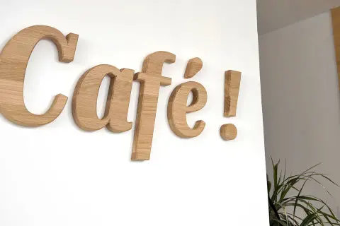Lettre en bois "Café !" sur un mur blanc. Ces lettres en bois, comme une lettre PVC, apportent une touche chaleureuse.